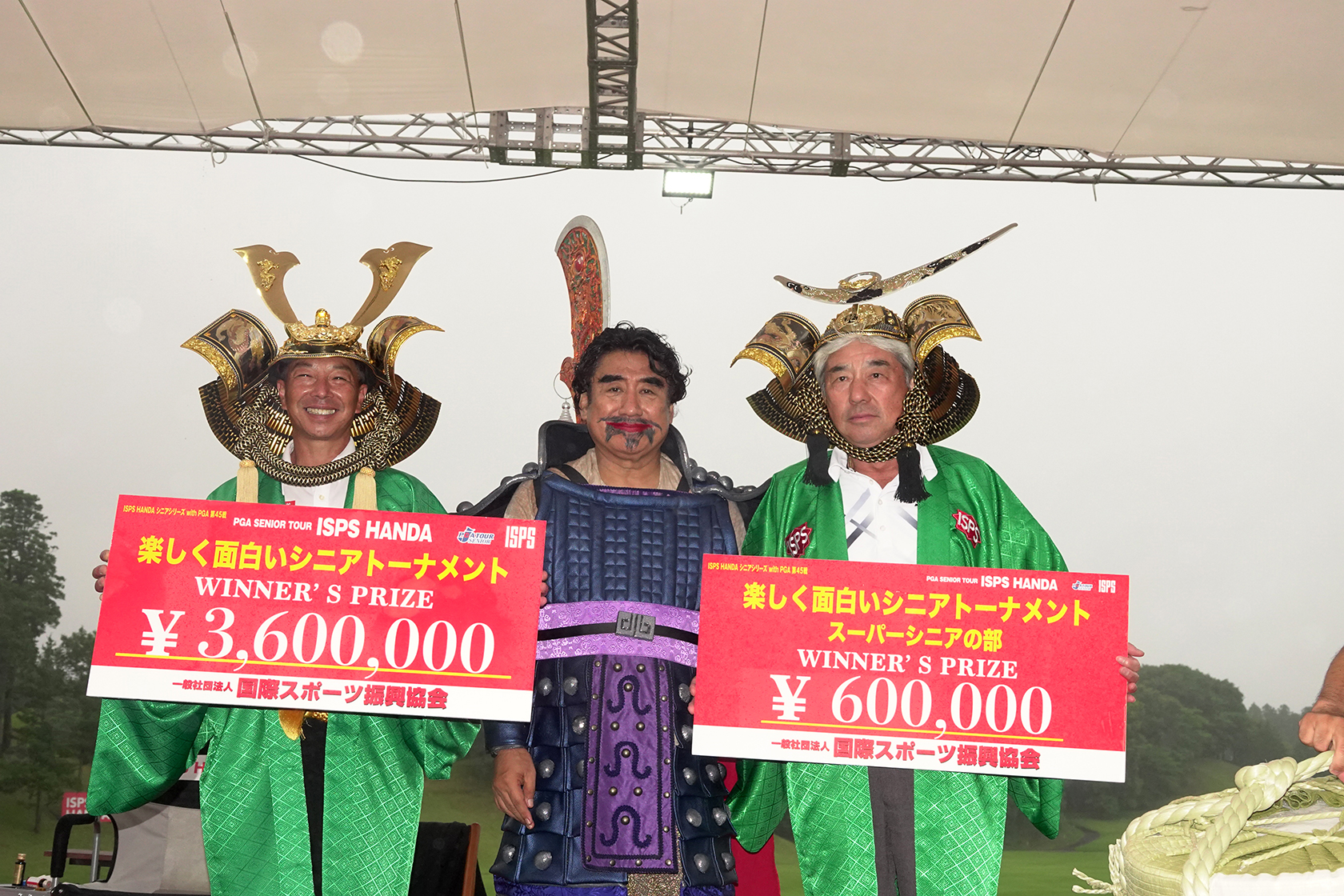 「ISPS HANDA楽しく面白いシニアトーナメント」のシニアの部で優勝したISPSインターナショナルアンバサダーの井戸木鴻樹（左）とスーパーシニアの部で優勝した福沢孝秋（右）。中央は国際スポーツ振興協会（ISPS）の半田晴久会長。